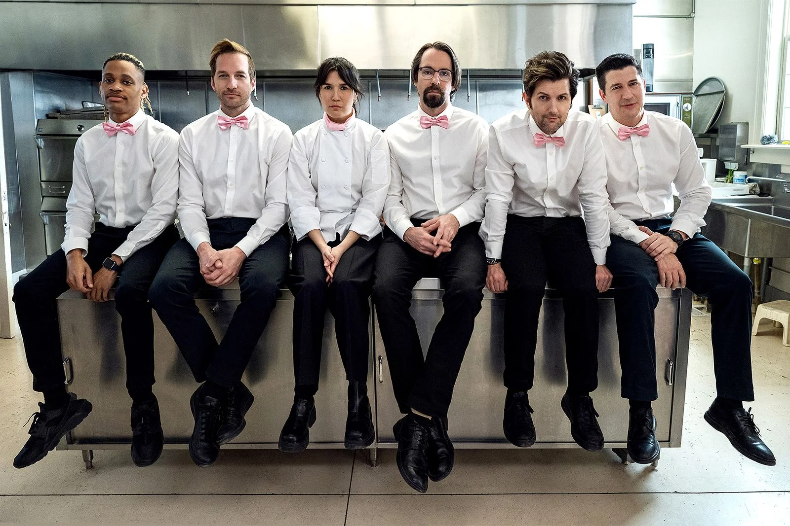 The cast of 'Party Down' dressed in formal wear sitting on a countertop inside of a kitchen