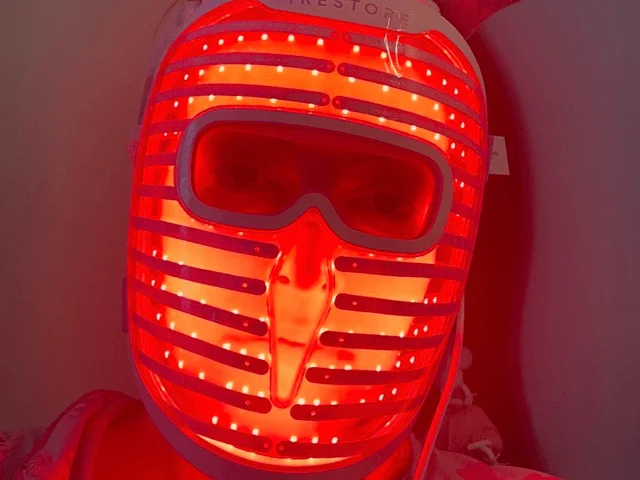 A person wearing an illuminated red light mask on their face
